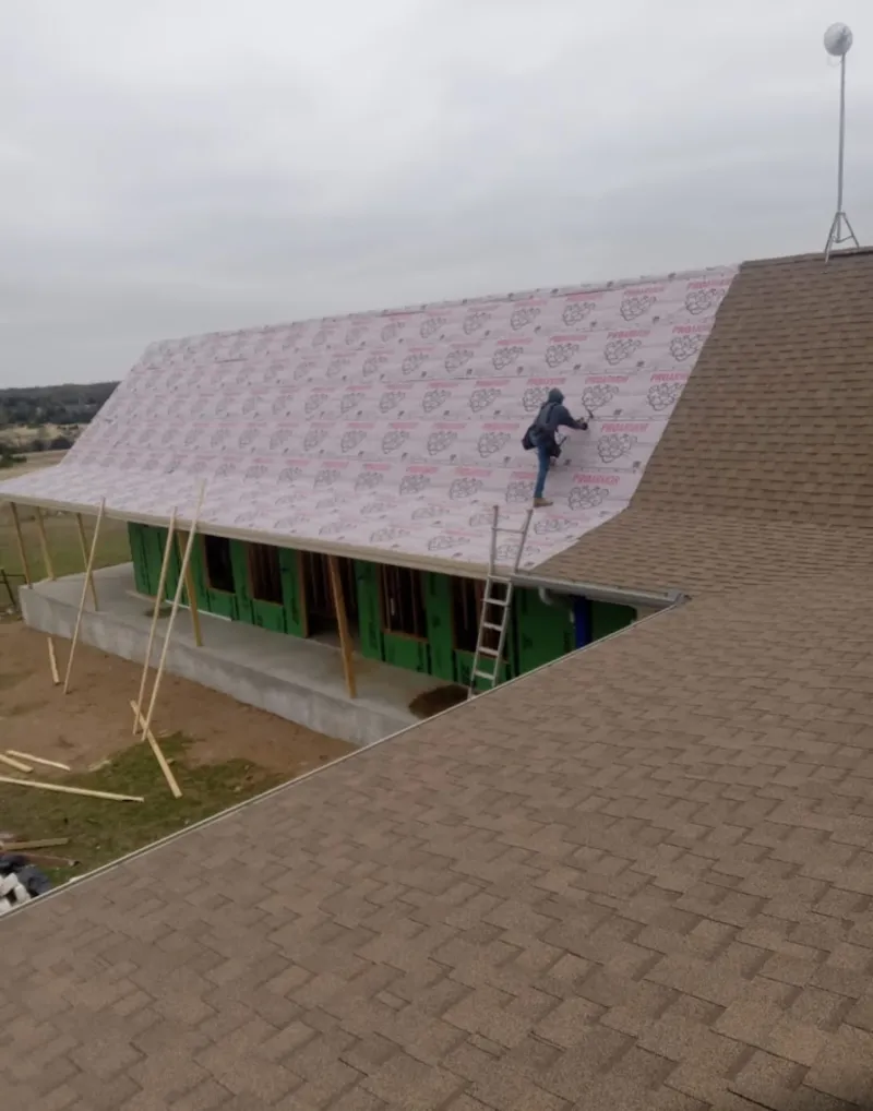 Worker preparing underlayment for a metal roof installation in Ramona